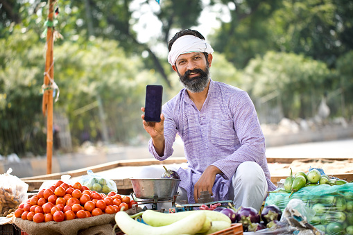 Indian street vegetable vendor showing mobile phone screen