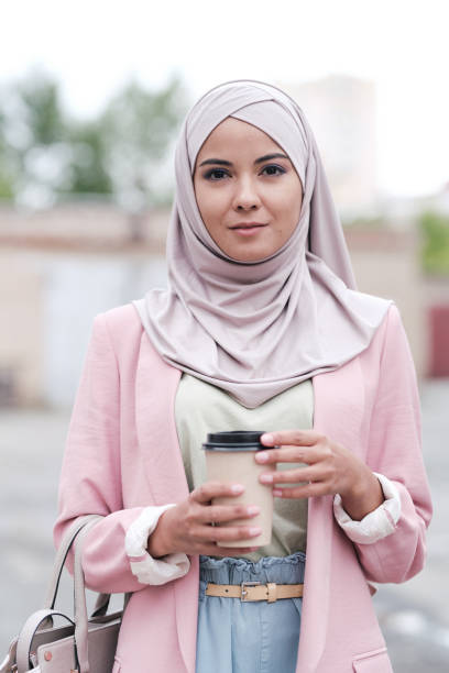 giovane splendida femmina in hijab, pullover, pantaloni e cardigan rosa che va a prendere un caffè - milfeh foto e immagini stock