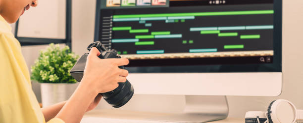 istock Hand holding camera and using application video editor works on the computer with footage on wooden table. 1280999668