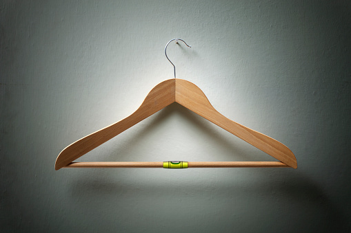 Wooden coat hanger with bubble level hanging on the wall.