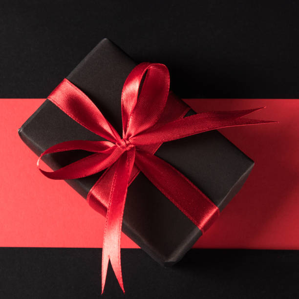 istock Gift box wrapped black paper and black bow ribbon present 1281000940