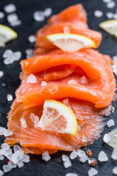 istock Smoked salmon with lemon and sea salt on black background. 1281006028
