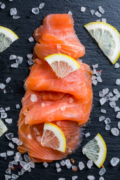 istock Smoked salmon with lemon and sea salt on black background. 1281006068
