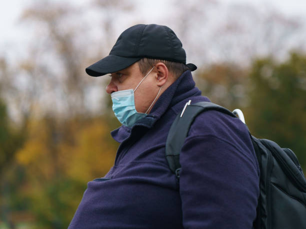 middle aged man wearing protective face mask outdoors - backpack one mature man only only mature men one man only imagens e fotografias de stock