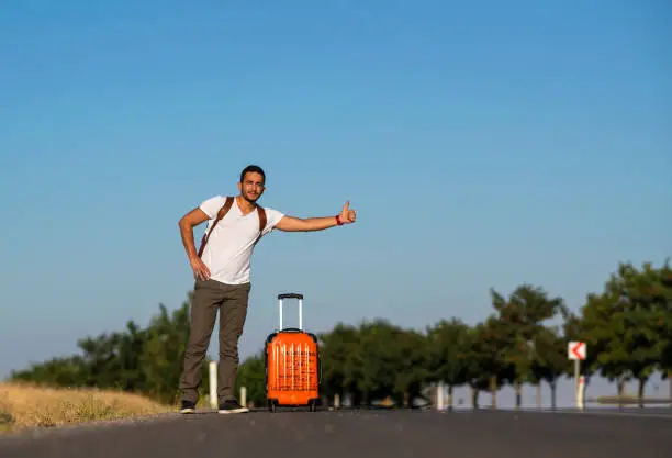 Young traveller hitchhiking on the roadside