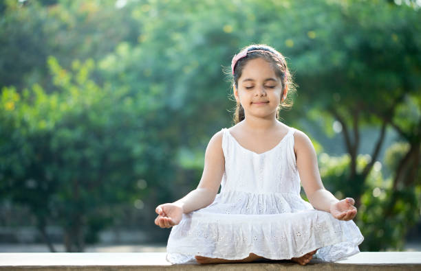 маленькая девочка медитирует на открытом воздухе в парке - zen like nature breathing exercise sitting стоковые фото и изображения