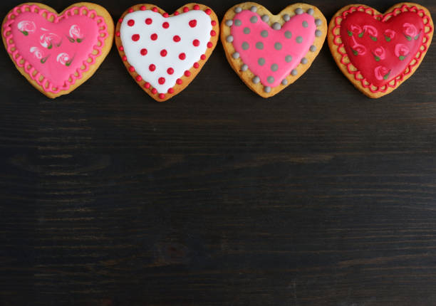 istock Heart shaped cookies with gorgeous patterns royal icing decoration lined up on black wooden background 1281011914