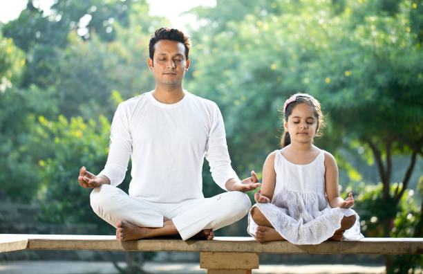 Father and daughter meditating outdoors at park