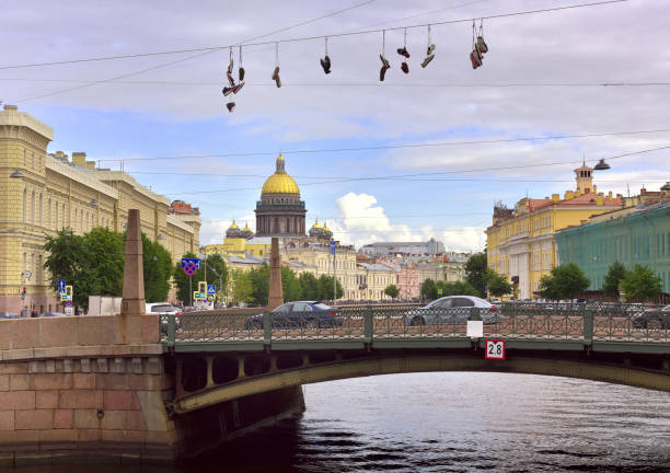 Saint Petersburg/Russia-09.01.2020: Old shoes hang on wires over the Moika river, the dome of St. Isaac's Cathedral in the distance. Student pranks