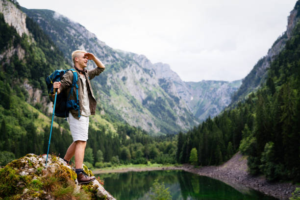 istock Handsome happy backpacker man hiking, camping through mountain forest. 1281013305