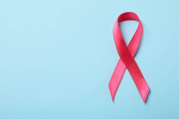istock Pink awareness ribbon on blue background, space for text 1281013802
