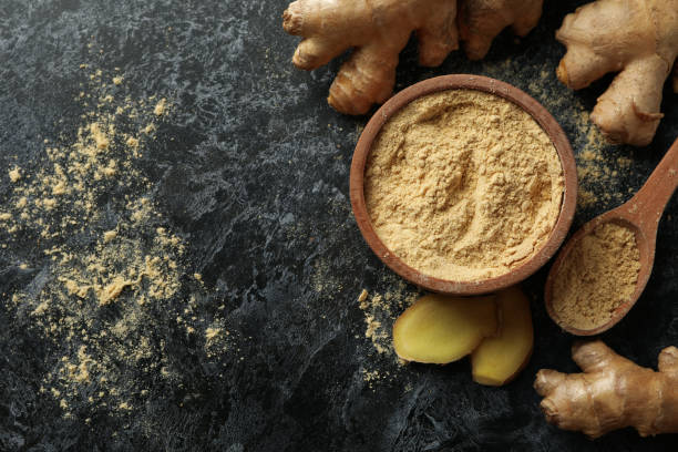 istock Ginger and bowl with ginger powder on black smoky background 1281014880