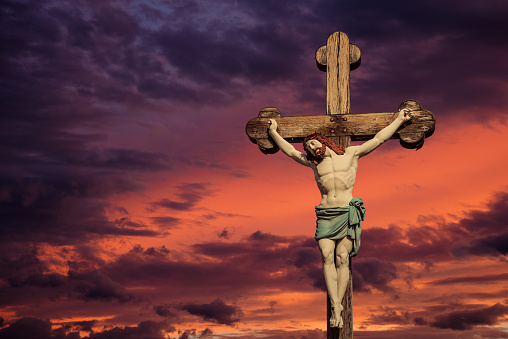Cross with Jesus Christ over sunset sky