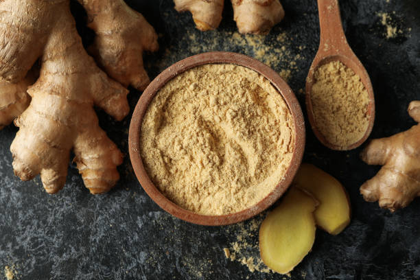 istock Ginger and bowl with ginger powder on black smoky background 1281016403