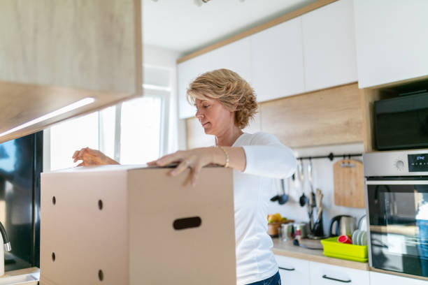 istock Woman closing cardboard box on the kitchen counter 1281017504