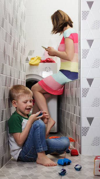 istock Child plays with capsules for washing while mom is distracted by talking on the phone 1281017832