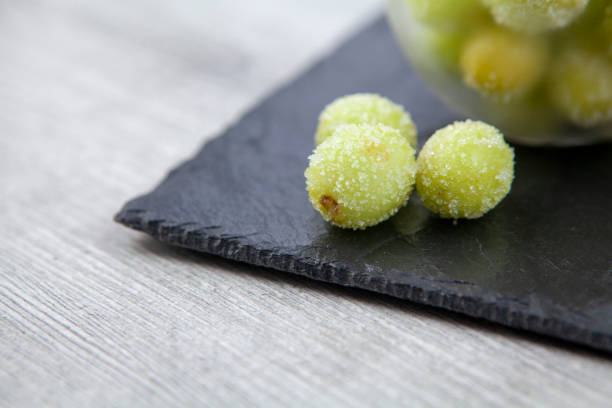 Sour candy grapes on slate surface Fashionable new recipe of frozen grapes coated in lime juice and rolled in sugar frozen grapes stock pictures, royalty-free photos & images