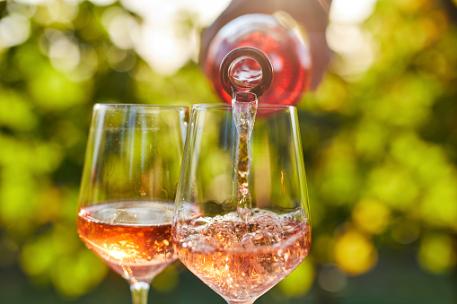 Pouring rose wine into glasses from a bottle