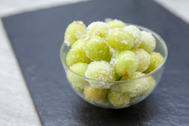 Sour candy grapes in a glass bowl on slate background Fashionable new recipe of frozen grapes coated in lime juice and rolled in sugar frozen grapes stock pictures, royalty-free photos & images