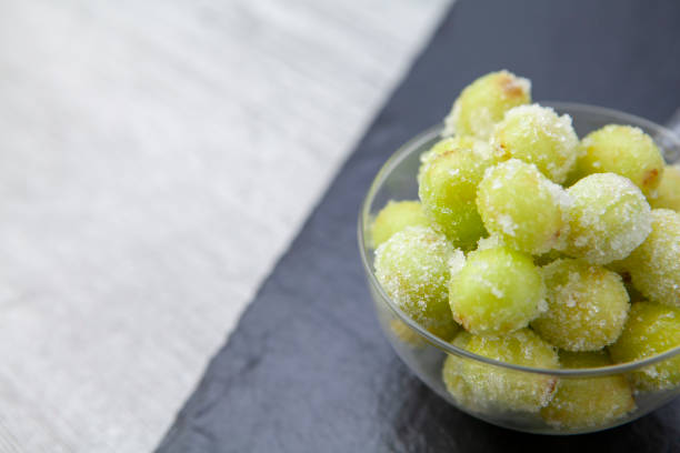istock Sour candy grapes in a glass bowl on slate background with copy space 1281019089