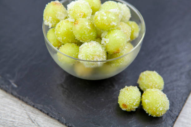 istock Sour candy grapes in a glass bowl on slate background 1281019231