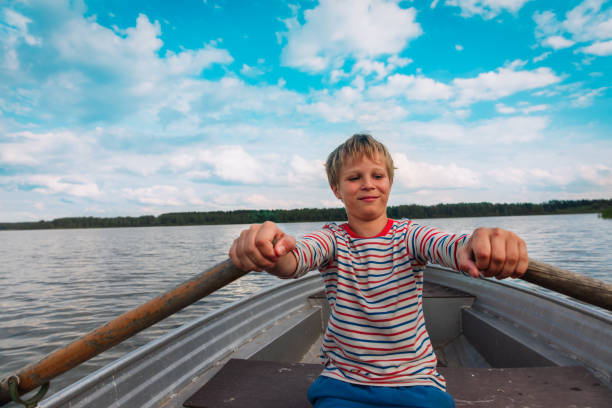 happy kid on boat ride in lake, boy exercise in nature