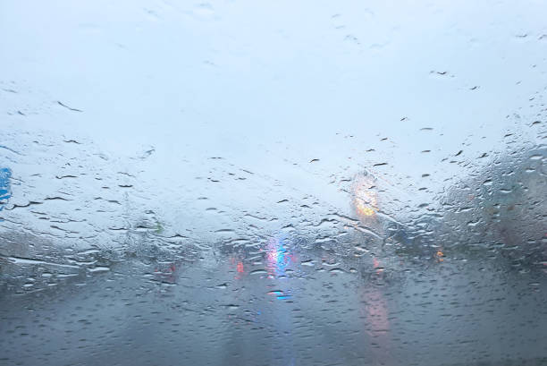 вид из автомобиля на капли дождя на окне и дороге с полицейскими огнями и силуэтами авт�омобилей, движущихся позади него в дождливое утро - traffic jam flash стоковые фото и изображения