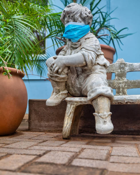 istock garden concrete statue with the face covered with a N95 surgical mask 1281020704