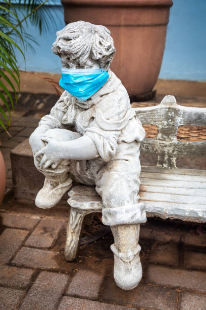 istock garden concrete statue with the face covered with a N95 surgical mask 1281020706