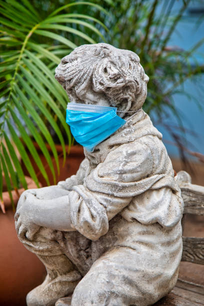 istock garden concrete statue with the face covered with a N95 surgical mask 1281020711