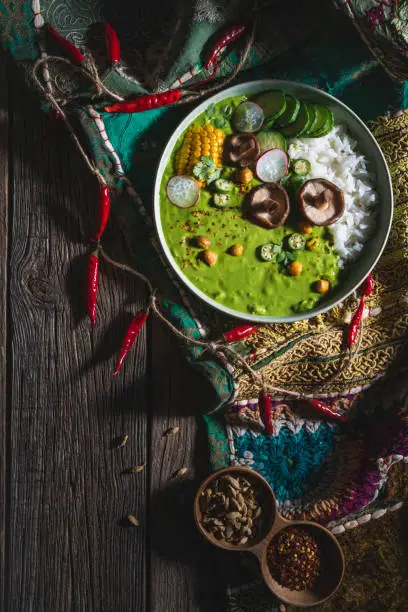 Thai green curry vegan bowl with basmati rice and corn, mushrooms, cucumber, chickpeas, radish, okra, coriander and chili peppers