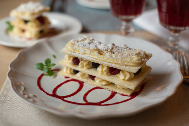 istock Mille-feuille cake - vanilla slice. Puff pastry with custard cream, berries and powdered sugar. Restaurant background. 1281028664