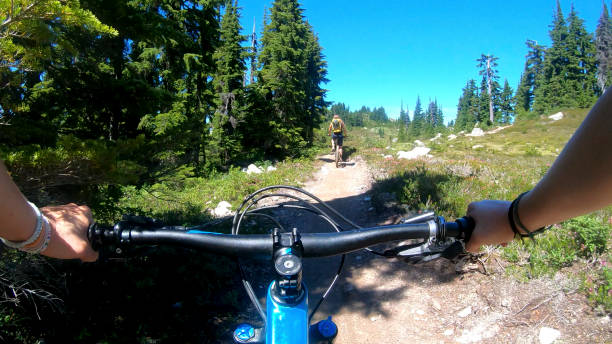 istock Female mountain bikers ride up sunny bicycle trail 1281030334