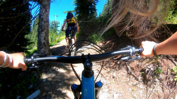 istock Female mountain bikers ride up sunny bicycle trail 1281032421