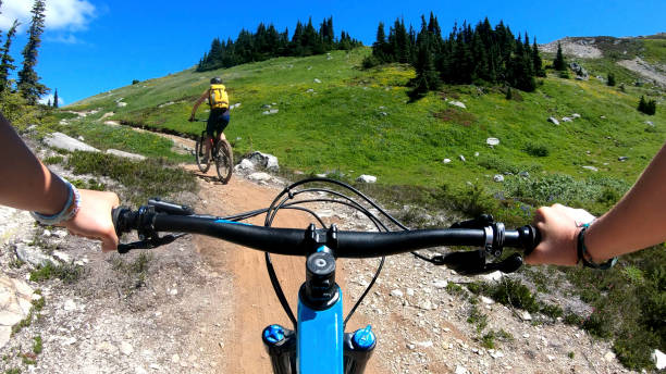 istock Female mountain bikers ride up sunny bicycle trail 1281032634