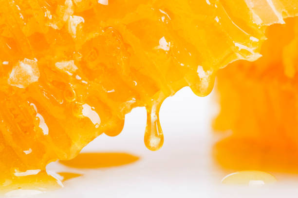 istock drop of honey flowing down from the honeycomb 1281034509