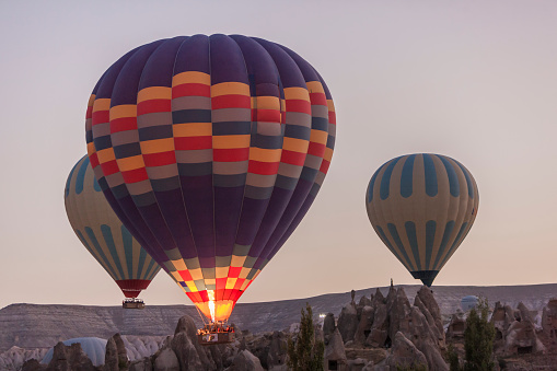 Hot air balloon landing in the middle of thicket, power lines and hills in background