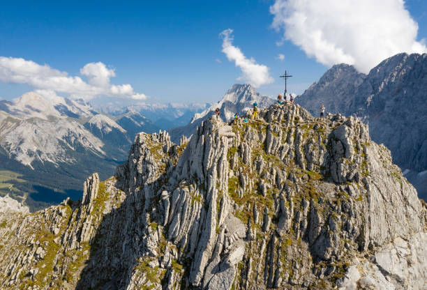 Hikers at the famous 2450m high Summit Cross of the Vorderer Tajakopf Mountain Peak, Mieming Chain, Tyrol, Austria. Converted from RAW. Unrecognizable hikers.