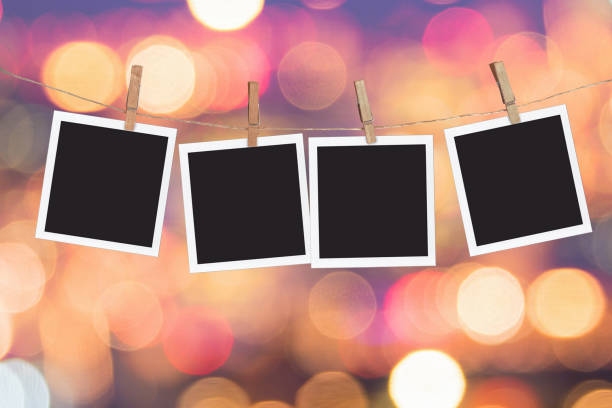 four blank instant photo frames hanging on a rope, on holiday lights bokeh background - hängen fotos stock-fotos und bilder