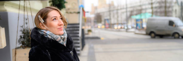 a beautiful young woman in fashionable winter fur coat waiting for a meeting on a city street. banner - individual event women people autumn imagens e fotografias de stock