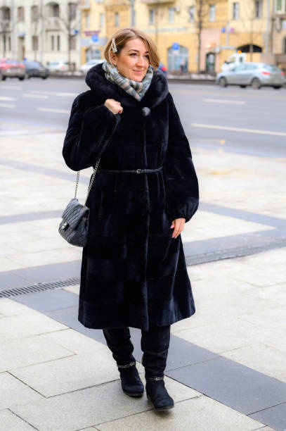 giovane donna felice in inverno alla moda pelliccia cammina lungo una strada della città - individual event women people autumn foto e immagini stock