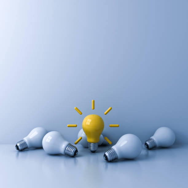 istock Standing out from the crowd concept bright yellow idea bulb with the dim unlit white bulbs on light blue background business creative idea concepts 1281043800