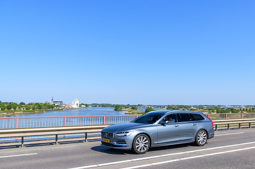 Volvo V90 luxury estate car driving on a bridge over the river IJssel during a beautiful summer day near Kampen, The Netherlands.