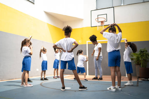 istock Physical activity teacher stretching arms with students at school 1281046478