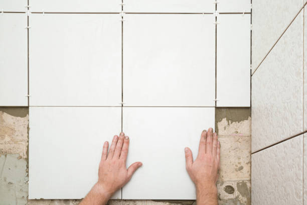 Worker hands gluing white ceramic tiles on floor. Closeup. Point of view shot. Top down view. Worker hands gluing white ceramic tiles on floor. Closeup. Point of view shot. Top down view. glue photos stock pictures, royalty-free photos & images
