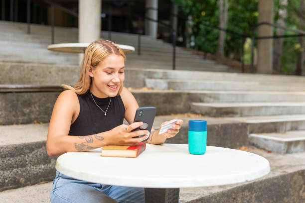 Young Maori Woman Making a Purchase Using a Credit Card and Their Phone Young Maori Woman Making a Purchase Using a Credit Card and Their Phone university students australia stock pictures, royalty-free photos & images