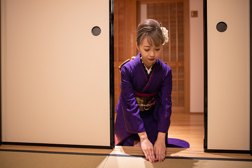 Young woman in ‘Furisode’ kimono bowing before entering Japanese ‘tatami’ room