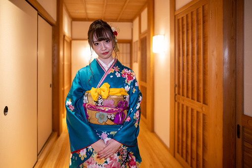 Portrait of young woman in ‘Furisode’ kimono standing on corridor in Japanese ‘ryokan’ hotel
