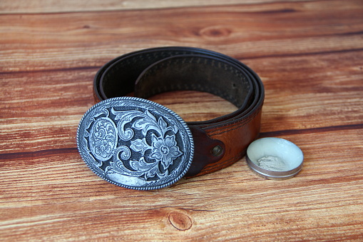 Leather cowboy belt with oval patterned buckle and cream for the leather products