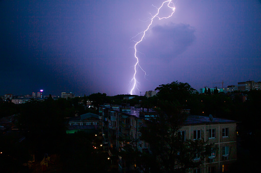 Lightning thunderstorm over the city rooftops in the night sky